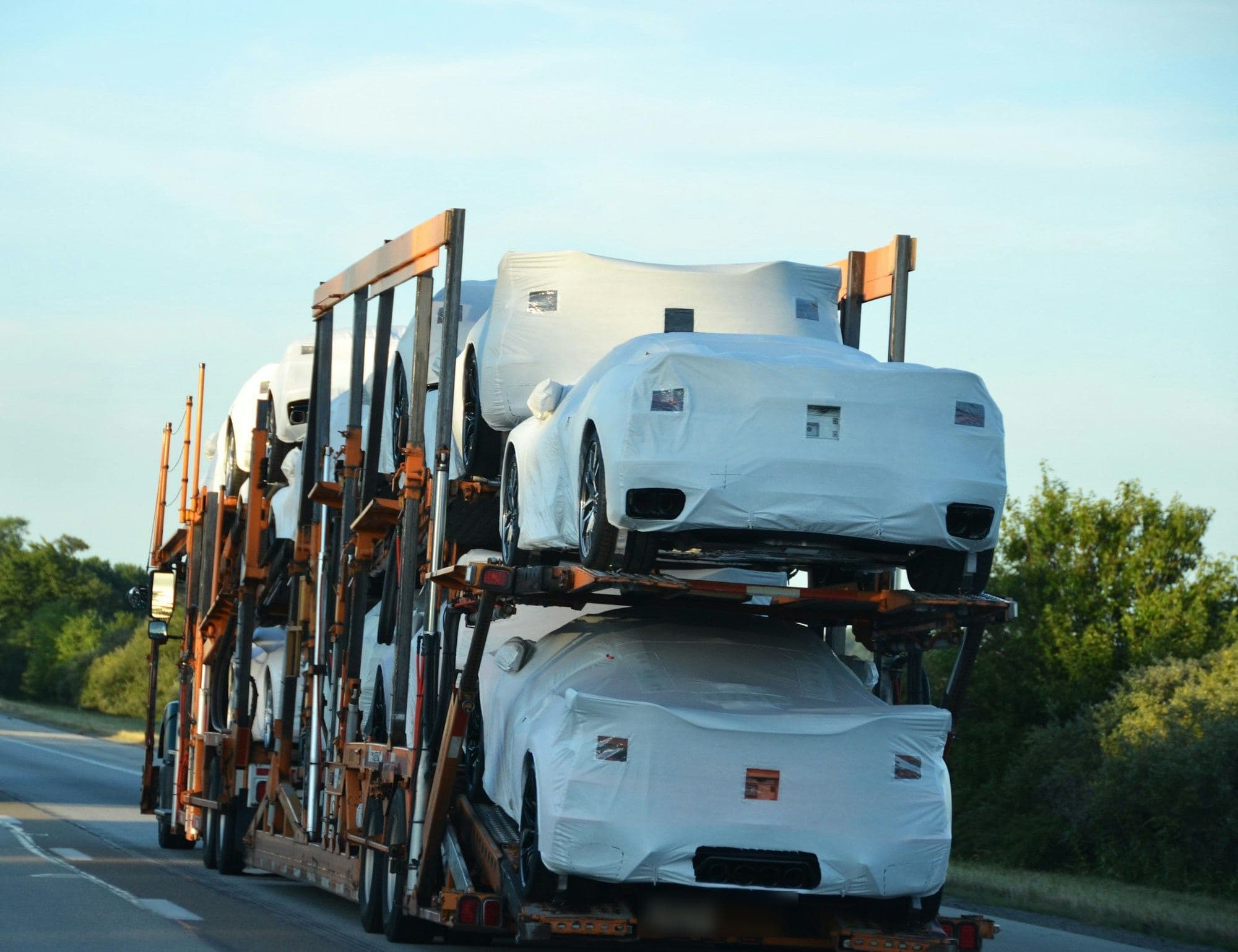 Porte-véhicules chargé de véhicules neufs protégés par des housses, sur l’autoroute